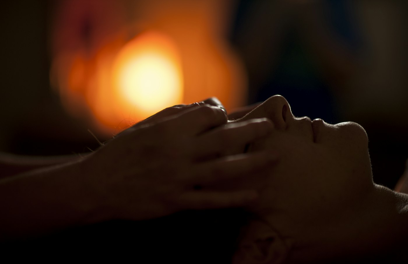 Hands giving a head massage in warm low light